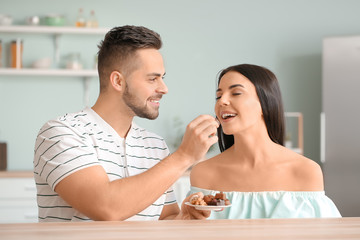 Beautiful young couple eating chocolate in kitchen