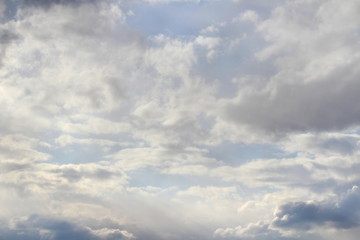 Clouds in the blue sky at sunset or dawn backlit by the sun. Place for text and design.