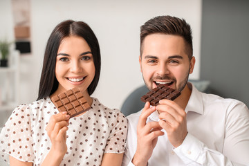 Beautiful young couple eating chocolate at home