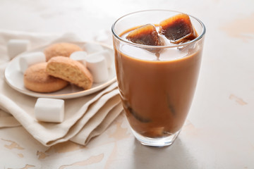 Glass of tasty iced coffee with sweets on white background