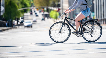 Woman in shorts takes a bike ride deputizing on a city street crossing the intersection