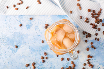 Mason jar of tasty iced coffee on color background