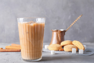 Glass of tasty iced coffee with cookies on grey background