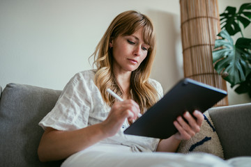 Woman using a stylus writing on a digital tablet  during coronavirus quarantine