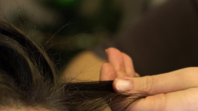 The stylist holds a lock of girl s hair in his hands and strokes her gently