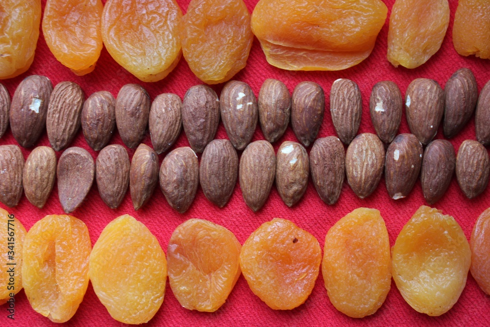 Wall mural almonds and dried apricots lined with a line on a red background. almonds and dried apricots close-u