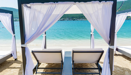 Fototapeta na wymiar Luxury Sunbeds with White Curtains on the Beach .Summer Holiday Concept