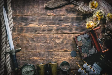 Fotobehang Pirate treasure chest with ancient coins and other various pirate equipment on flat lay table background. © Dmitriy