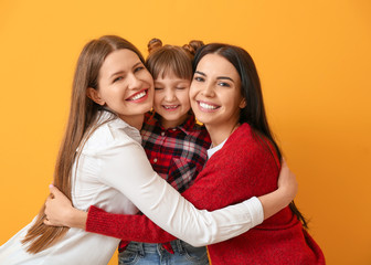 Happy lesbian couple with little adopted girl on color background