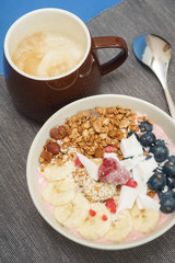 Handmade Bowl healthy tasty breakfast of yogurt, smoothie with granola, nuts, bananas and berries