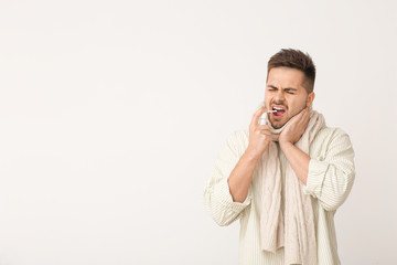 Ill young man with inhaler on light background