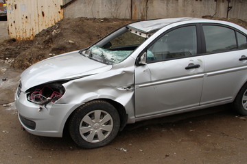 A broken silver car after an accident on the road. Transport security concept.