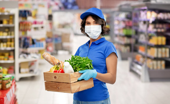 health protection, safety and pandemic concept - delivery woman in face protective medical mask and gloves holding wooden box with food over supermarket or grocery store background