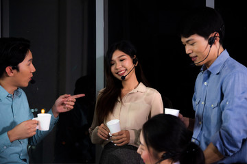 Asian call center business people are talking together and have coffee break during working late night shift in workplace at night time