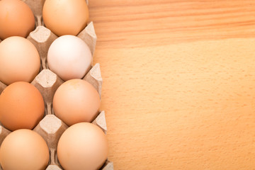 brown chicken eggs in an open cardboard box with eggs on a wooden table. Natural healthy food.