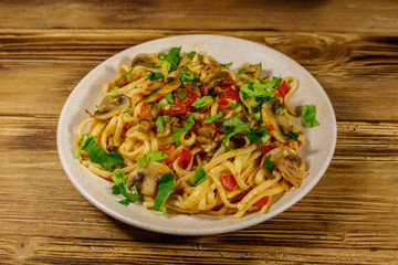 Pasta with mushrooms and tomato sauce on wooden table
