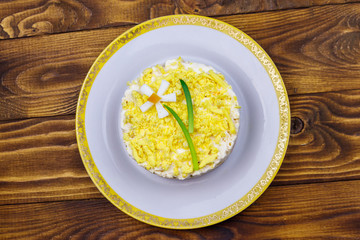 Traditional russian layered salad Mimosa with spring decoration Daffodil. Decoration is made of egg, green onion and carrot. Top view
