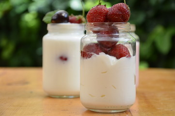 Healthy breakfast home made pudding or yogurt or granola, strawberries, cherry, berry,  yogurt in a bowl. Vegetarian concept food. pudding or cocktail on of green foliage