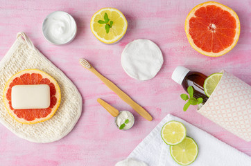 Zero waste bathroom accessories soap, toothbrush, toothpaste, shea butter, soap,  washcloth, reusable glass container with shampoo, cotton pads, some citrus fruits around. Top view, layout. 