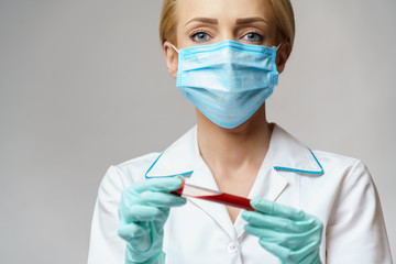 medical doctor nurse woman wearing protective mask and gloves - holding virus blood test