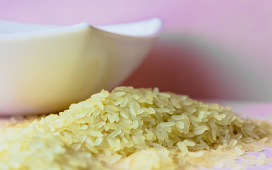 close up of white rice with white cup on pink background. 