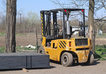 Old ruined forklift outdoor next to trees