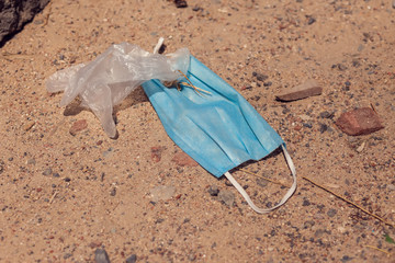 Used medical masks and gloves on ground on the street. Environmental pollution concept
