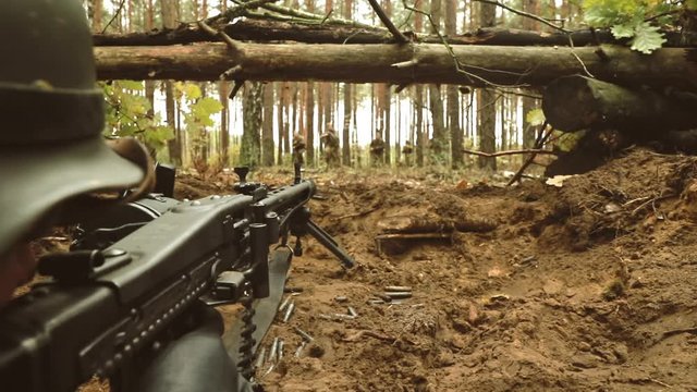 Historical Re-enactment. Re-enactor Dressed Like German Wehrmacht Infantry Soldier In World War II Shooting machine gun from Forest entrenchment. slow mo, slow motion, motion, slow, slo-mo, slow-mo.