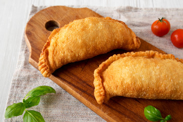 Homemade Deep Fried Italian Panzerotti Calzone on a rustic wooden board on a white wooden background, side view. Close-up.