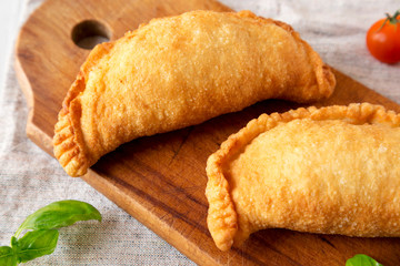 Homemade Deep Fried Italian Panzerotti Calzone on a rustic wooden board, low angle view. Close-up.