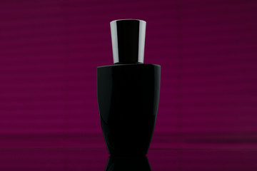 Bottle of black perfume in pink background. Cosmetic perfume black