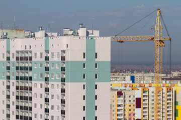 Fototapeta na wymiar Construction crane and built multi-storey residential building against the background of built-up city