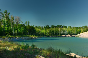 Lake at the quarry site in the forest with emerald water