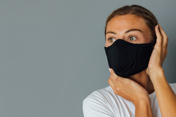 young woman wears a protective mask against the spread of the virus. Staying at home, self-isolation, coronavirus, pandemic