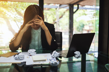 Businesswoman get stressed with screwed up papers and laptop on table while having a problem at work in office