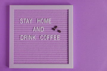 Quote stay home and drink coffee on purple decorative board. decoratin with coffee beans. Typography board for interior decoration.