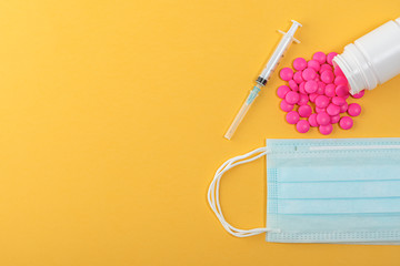 Medical mask surgical protective virus, flu, disease, pills and syringe. Isolated on a yellow background.
