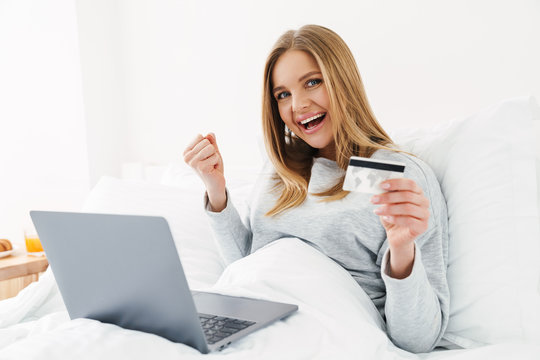 Image of excited woman holding credit card and making winner gesture
