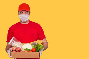 A courier employee in uniform holds a cardboard box with food isolated. Service quarantine pandemic...