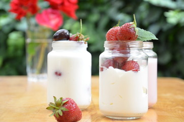 Healthy breakfast home made pudding or yogurt or granola, strawberries, cherry, berry,  yogurt in a bowl. Vegetarian concept food. pudding or cocktail on of green foliage