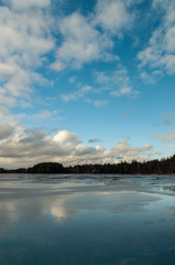 winter landscape with a frozen lake and clouds above it