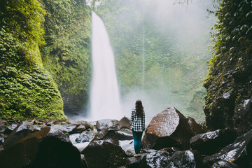 Waterfall in tropical jungle and alone woman. Waterfall in Bali