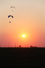 Motodeltaplanerists in the sky at sunset