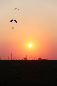 Motodeltaplanerists in the sky at sunset