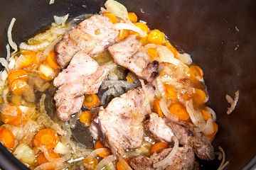 Cooking. Roasting pieces of meat with carrots or onions in a multicooker bowl