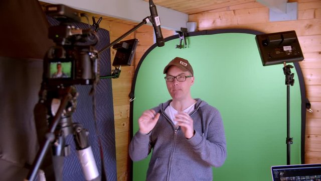 Male YouTuber presents excitedly to camera with dynamic hand gestures in front of green screen.