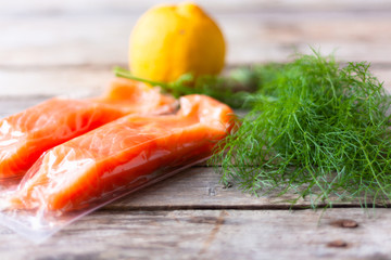 Red fish o salmon fillets in vacuum package on white background. Fresh fish, lemon and dill for cooking ingredients. Concept of healthy eating. Omega-3. Selective focus. Close up. Copy space