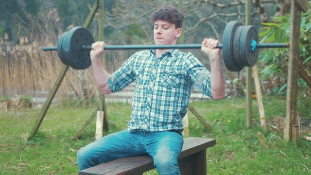 Home gym weight training young man doing military and behind neck press