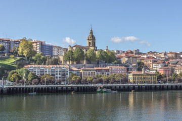 Obraz premium Euro-trip. The ancient city of Spain. City on the banks of the river Nervion. The city of Portugal in the Basque Country. Houses with red tiles. Dome of the catholic cathedral in cityscape.