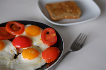 Fried eggs with tomatoes and bread for breakfast on a white background.